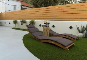 a wooden bench sitting on grass next to a wall at Malakion Lux Seaside Jacuzzi in Malaki
