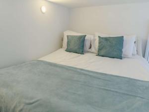 a white bed with blue pillows on top of it at 1 Bed in Tresaith 89316 in Penbryn