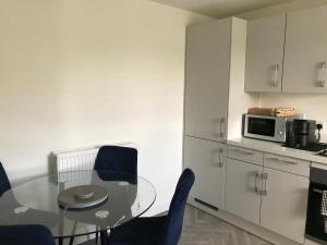 a kitchen with a glass table and chairs and a microwave at Sweet Haven in Sittingbourne