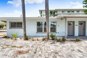 a white house with palm trees in front of it at Sun and Sea By Beachside Management in Siesta Key