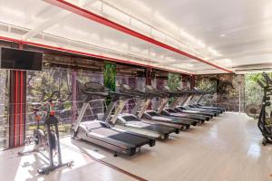 a gym with a row of tread machines and a tv at Suíte em Condomínio de Luxo em Casa de Família in Araras Petropolis