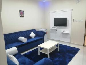 a living room with a blue couch and a table at برج الشارقة للشقق المخدومة in Najran