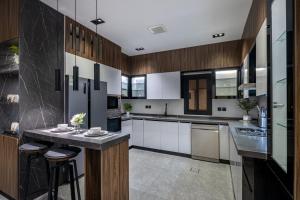 a kitchen with white cabinets and a island with bar stools at Super Luxury SweetHome in Medina
