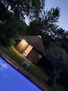a small house with a thatch roof next to a pool at Afpak in Barberton