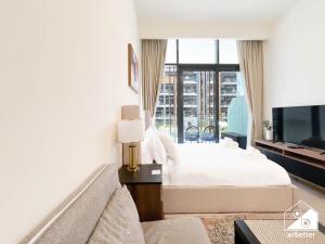 a bedroom with a white bed and a large window at Urban Charm Studio with Balcony in Azizi Riviera in Dubai