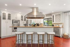 Una cocina con gabinetes blancos y taburetes de bar. en Palm-Lined Spanish Oasis w Pool Spa BBQ Games Near Coachella, en Indio