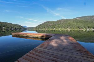 een dok op een meer met bergen op de achtergrond bij Wilderness West Resort Cabin 6 in Colville