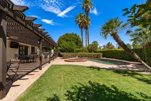 un patio trasero con piscina y palmeras en Palm-Lined Spanish Oasis w Pool Spa BBQ Games Near Coachella, en Indio