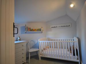 a white nursery with a crib and a chair at 2 Bed in Winchcombe 47951 in Winchcombe