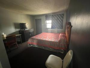 Un pequeño dormitorio con una cama y un televisor. en Capital O Empire Motel Chicago I-94, en Calumet Park