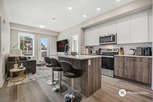 eine Küche mit weißen Schränken und Barhockern in der Unterkunft Luxury Getaway in Inglewood with 2 Bedrooms Sofa Bed and Heated Underground Parking in Calgary