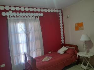 a bedroom with a red bed and a window at Departamento de los pájaros in Córdoba
