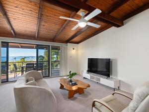 a living room with a ceiling fan and a flat screen tv at Coastal Family Escape with Pool Balcony and Bay Views in Ormiston