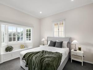 a white bedroom with a large bed and two windows at Spacious 4-Bedroom Bardon Retreat Across 2 Levels in Brisbane