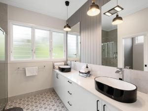 a bathroom with a sink and a large mirror at Spacious 4-Bedroom Bardon Retreat Across 2 Levels in Brisbane +13 photos
