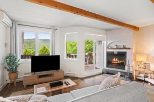 a living room with a television and a fireplace at Stunning One-Bedroom Condo With Lake View in Mont-Tremblant