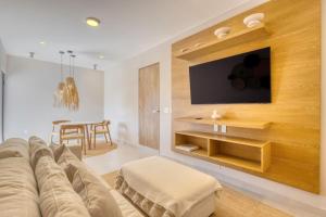 a living room with a couch and a tv on a wall at New and Elegant 4Bedroom House Steps from the Beach in Cabo San Lucas