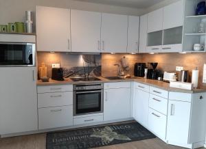 a white kitchen with white cabinets and appliances at Tillmanns Stadtlounge in Norden