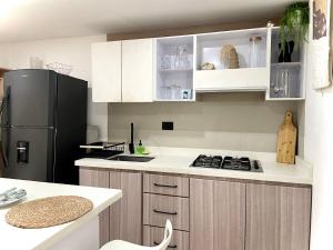 a kitchen with white cabinets and a black refrigerator at Hermoso Apartamento cerca a la playa in Cartagena de Indias