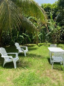 three white chairs and a table in the grass at Maison charmante à Baie-Mahault avec jardin clôturé in Baie-Mahault