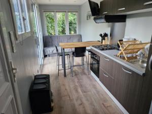 a small kitchen with a wooden table in a tiny house at Domaine du Bois l'Abbé - La Cabane in Saint-Martin-Boulogne