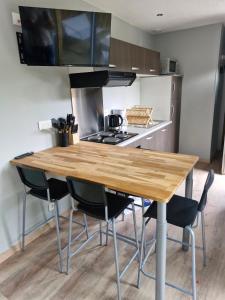 une cuisine avec une table en bois et des chaises noires dans l'établissement La Cabane du bois l'abbé, à Saint-Martin-Boulogne 12 autres photos