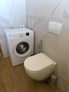 a bathroom with a toilet and a washing machine at Margo Sea View Studio in Gjuricaj