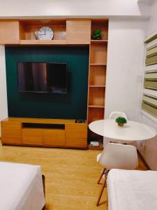 バギオにあるCEDAR PEAK by AWESOME STAY in Baguioのテレビとテーブルと椅子のあるリビングルーム