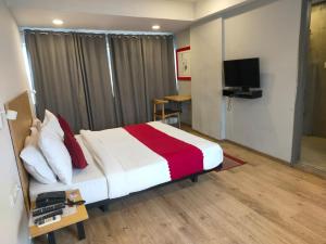 a hotel room with a bed and a television at SwagStay Hotel Century, Nagpur in Nagpur +5 photos