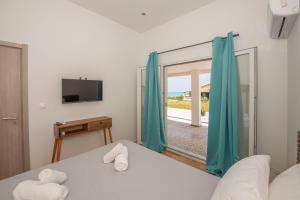 a room with a bed and a tv and a window at Massalia Suites in Agios Stefanos