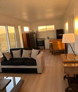 a living room with a couch and a kitchen at Lindas y acogedoras cabañas en puerto varas. in Puerto Chico