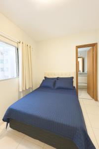a bedroom with a blue bed and a window at Apto 5 minutes Ufu, 7 minutes Sabia Park in Uberlândia