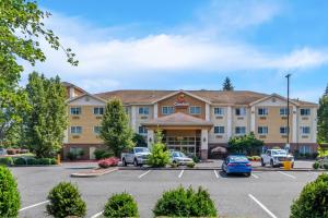 a hotel with cars parked in a parking lot at Comfort Suites Clackamas in Clackamas