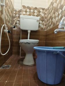 a bathroom with a toilet and a blue bucket at Murugavel Residency in Vishāram