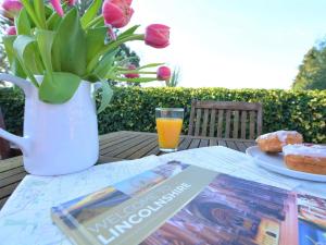 a table with a book and a vase of flowers and orange juice at 2 Bed in Lincoln 73853 in East Barkwith +12 photos
