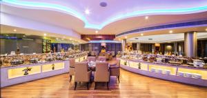 un ristorante con un lungo bar con tavoli e sedie di Clarks Exotica Convention Resort & Spa a Devanhalli