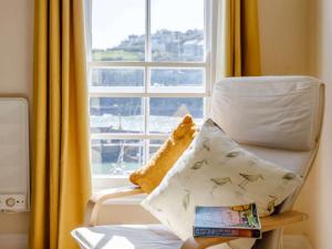 a chair with a pillow in front of a window at 2 Bed in Mevagissey MEVAC in Mevagissey