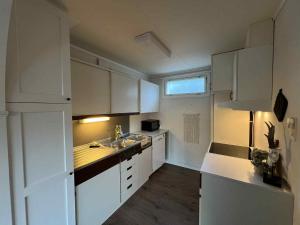 a white kitchen with white cabinets and a sink at Fonnagata in Åndalsnes +1 photo