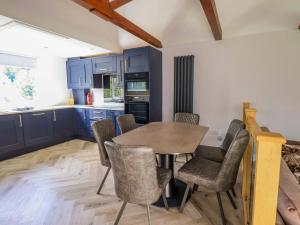 a kitchen with blue cabinets and a table and chairs at Mallard Cottage in Penrith