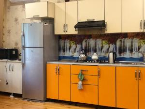 a kitchen with orange cabinets and a stainless steel refrigerator at Кюнгют Гостевой дом in Sheki