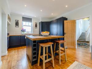 a kitchen with blue cabinets and a counter with stools at 4 Bed in Bexhill on Sea 77602 in Bexhill +17 photos
