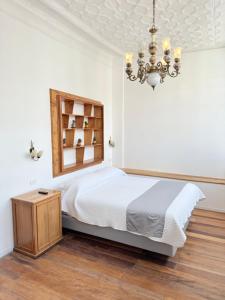 a white bedroom with a bed and a chandelier at Casa Vega in Cuenca