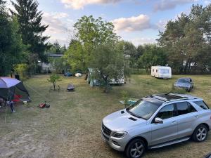a white suv parked in front of a camp site at Pole kempingowe Zalewowa Gruszka in Styków