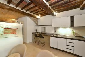 Una cocina con gabinetes blancos y taburetes de bar. en Auditorium Rooms, en Foligno
