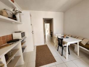 Il comprend un salon avec une table blanche et une cuisine. dans l'établissement La Casa Rosie, charme paisible à Palavas les Flots, à Palavas-les-Flots 9 autres photos