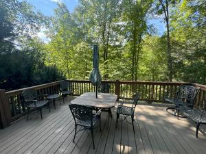 un tavolo con sedie e un ombrellone su una terrazza di Hummingbird Hideaway - Lake Pets Hike Fish a Hidetown Altre 12 foto