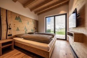 une chambre avec un lit et une grande fenêtre dans l'établissement Stabingerhof Chalets & Apartment-Farm stay, à Bressanone
