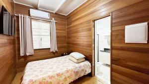 a small bedroom with a bed and a window at Piscina aquecida - Sol e mar House Guaratuba in Guaratuba