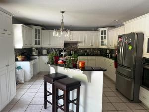 a kitchen with white cabinets and a black refrigerator at peaceful stay in Stanley Bridge