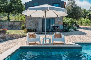 two chairs and an umbrella next to a swimming pool at Villa Seara - Casas da Vinha in Celorico de Basto